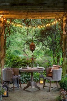 an outdoor dining area with wicker furniture and string lights strung across the pergolated arbor