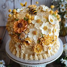 a cake decorated with flowers, bees and daisies