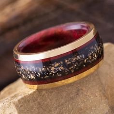 a red and black ring sitting on top of a rock