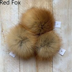 three fur pom - poms sitting on top of a wooden floor