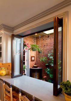 a kitchen with an open door leading into the dining room and living room area that has potted plants on the counter