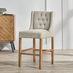 an upholstered bar stool sits in front of a dresser