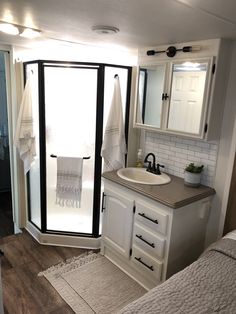 a bathroom with a sink, mirror and towel rack in it's corner next to a shower door