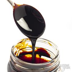 a spoon full of liquid pouring into a jar