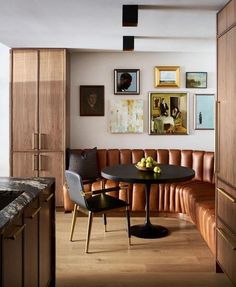 a kitchen area with a table, chairs and pictures on the wall