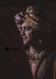 a woman wearing an elaborate headdress and jewelry in front of a dark background