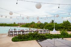 an outdoor dining area with tables and chairs next to the pool is decorated with paper lanterns