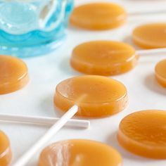 several candies are lined up on a table next to a glass with a straw in it