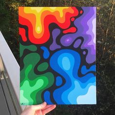 a person holding up a colorful piece of art with trees in the back ground behind them