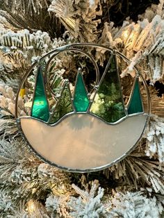 a stained glass ornament hanging from a christmas tree with snow on the branches