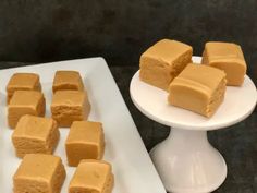 several pieces of cake on a plate next to a small white platter with squares of frosting