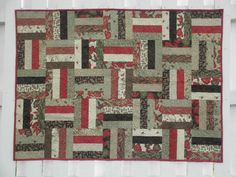 a patchwork quilt hanging on the side of a white building with red and green accents