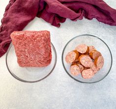 two glass bowls filled with meatballs next to a red napkin on a white surface