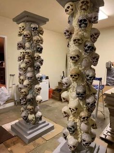 two tall sculptures made out of skulls sitting on top of each other in a room