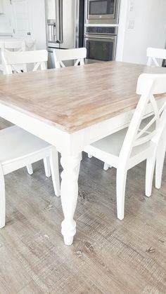 a kitchen table with white chairs around it and a stove in the backround