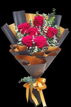 a bouquet of red roses and greenery wrapped in brown paper with yellow ribbon on black background