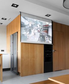 a large screen mounted to the side of a wall in a room with wooden cabinets