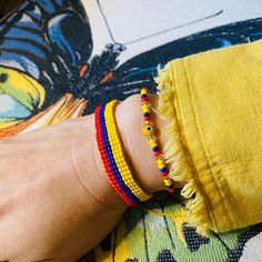 a person's hand with colorful bracelets on their wrist and the other arm