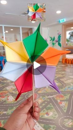 a hand holding a multicolored paper pinwheel