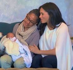 two women sitting on a couch with a baby in their lap and one woman holding the baby