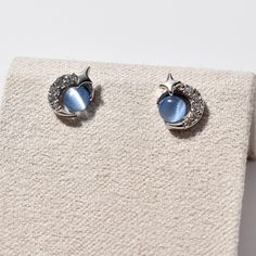 Introducing our Star, Moon, and Blue Planet Stud Earrings - a celestial trio that's out of this world. Each earring features a unique combination of a star, a moon, and a captivating blue planet made from a glass cat's eye stone, offering an enchanting, starry-night aesthetic. The crescent moon is intricately adorned with an array of small zirconias, delicately catching the light for an irresistible sparkle. These earrings are a perfect accessory for those who want to carry a touch of the cosmos Blue Star-shaped Sterling Silver Earrings, Blue Celestial Pierced Earrings, Celestial Blue Pierced Earrings, Blue Celestial Round Earrings, Blue Sterling Silver Star Earrings, Blue Celestial Hypoallergenic Jewelry, Blue Star-shaped Celestial Earrings, Hypoallergenic Blue Star Earrings, Earrings Zirconia