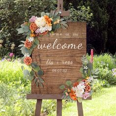 a welcome sign with flowers and greenery on it