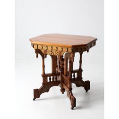 a small wooden table with carvings on the top and bottom, against a white background