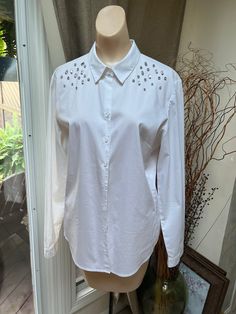 "The next time you think about a white shirt (who doesn't?) think about a touch of bling for fun.  Never worn shirt perhaps because it has a size L tag but it's really a M.   Blend of cotton, polyester and 5% spandex.   So the blouse will stretch but I don't think up to a size L. A little bit of silvery clear crystals on the upper shoulder area in different shapes, mostly rectangles and rounds.   All are prong set and handsewn.  Because of the gems you'll need to hand wash the shirt and air dry. Spring Embellished Fitted Shirt, White Long Sleeve Embellished Shirt, White Embellished Long Sleeve Shirt, Embellished Fitted Shirt For Workwear, Long Sleeve Cotton Top With Embellished Collar, Long Sleeve Cotton Tops With Embellished Collar, White Embellished Top For Work, White Top With Embellished Collar For Work, White Long Sleeve Tops With Embellished Collar