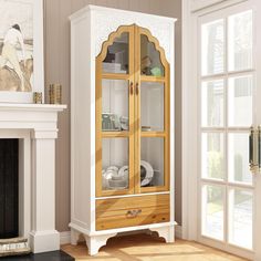 a white and wood china cabinet in a living room next to a fire place with a painting on the wall