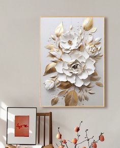 a white and gold flower is hanging on the wall next to a vase with flowers in it