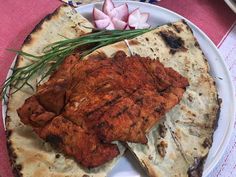 a white plate topped with meat and pita bread