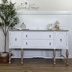 a white dresser sitting next to a potted plant