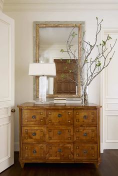 a wooden dresser with a mirror on top of it and a lamp next to it