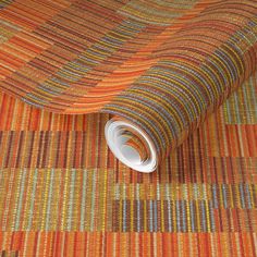 an orange, yellow and green striped carpet with a roll of paper on the floor