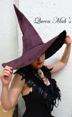 a woman wearing a purple witches hat with feathers