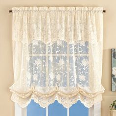 a window with a white lace curtain hanging from it's side, and a potted plant in front of the window