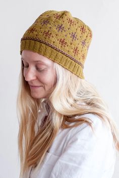 a woman with blonde hair wearing a knitted hat and looking down at her cell phone