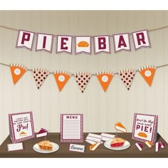 a table topped with lots of food next to bunting and paper signs that say pie bar