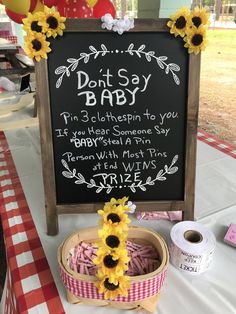 a sign that says don't say baby and sunflowers are on the table