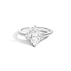 a three stone engagement ring with two pear shaped diamonds on the band and an oval diamond center