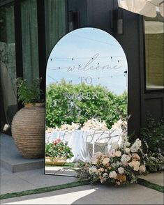 a large mirror sitting on the side of a building next to a flower pot and table