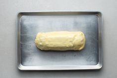 a doughnut sitting on top of a metal pan covered in yellow frosted icing