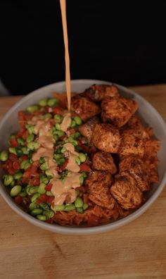 a bowl filled with meat and vegetables on top of a wooden table