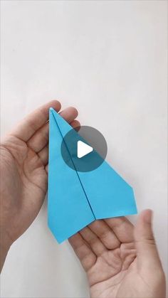 someone is holding an origami airplane in their hand and pointing it at the camera