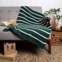 a green and white blanket sitting on top of a couch next to a wooden table