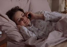 a woman laying in bed talking on the phone