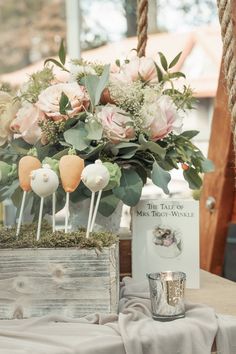 an arrangement of flowers and candles in a wooden box on a table next to a card