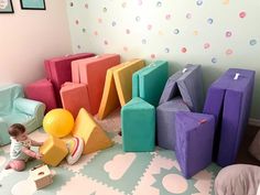 a baby playing with blocks and balls on the floor in front of a colorful wall