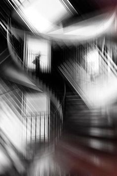 black and white photograph of stairs in an apartment building, with blurry image behind them