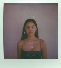 a woman standing in front of a wall with her head tilted to the side and looking at the camera